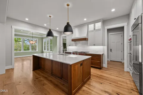 a kitchen with stainless steel appliances granite countertop a sink a stove and a wooden floors