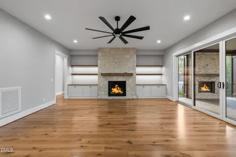 a view of an empty room with wooden floor and a fireplace