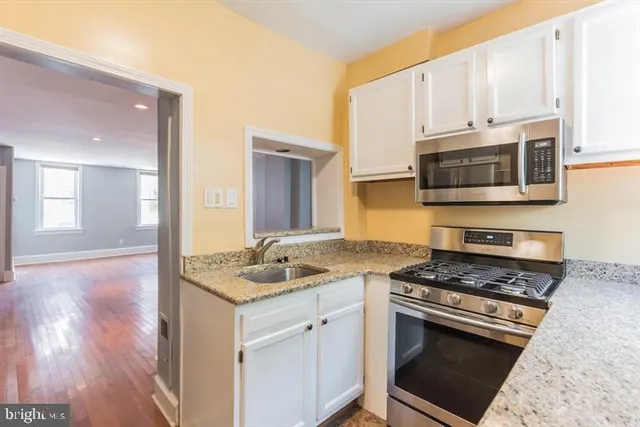 a kitchen with granite countertop a sink cabinets and stainless steel appliances