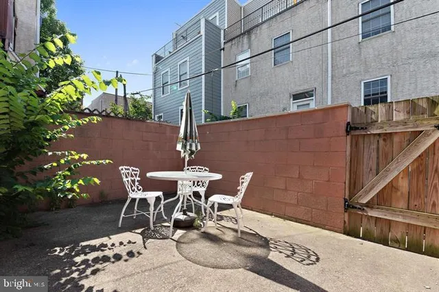 a patio with table and chairs and potted plants