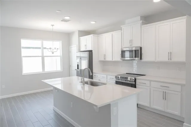 a kitchen with stainless steel appliances granite countertop a sink a stove and white cabinets