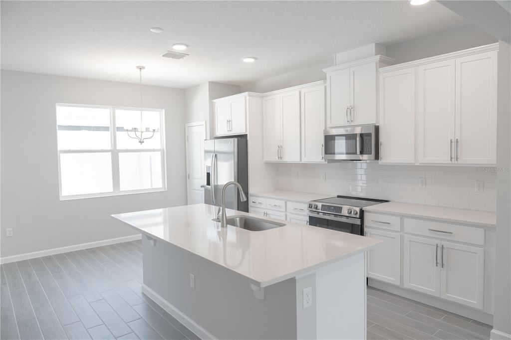 583 Pothos Street Apopka, FL 32703 - Photo 5 of 26 a kitchen with stainless steel appliances granite countertop a sink a stove and white cabinets