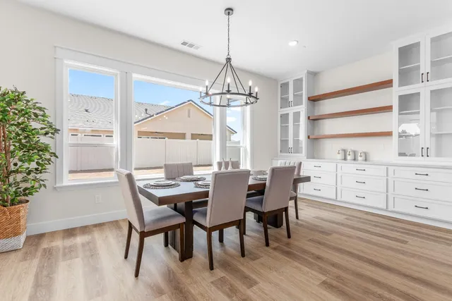 a dining room with wooden floor a chandelier a wooden table and chairs