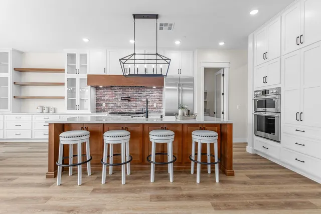 a kitchen with stainless steel appliances kitchen island granite countertop a table chairs sink and cabinets