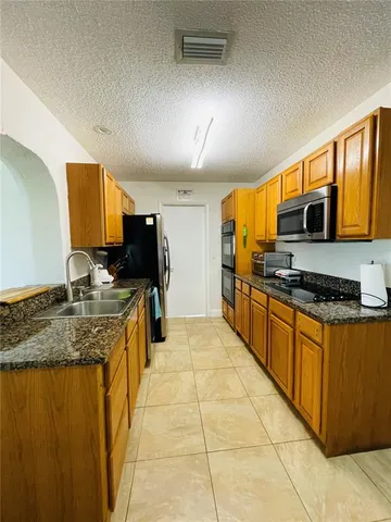 a large kitchen with kitchen island granite countertop a stove top oven a sink dishwasher a dining table and chairs with wooden floor