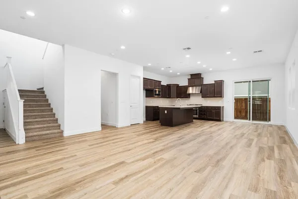 a large kitchen with kitchen island a sink wooden floor and stainless steel appliances