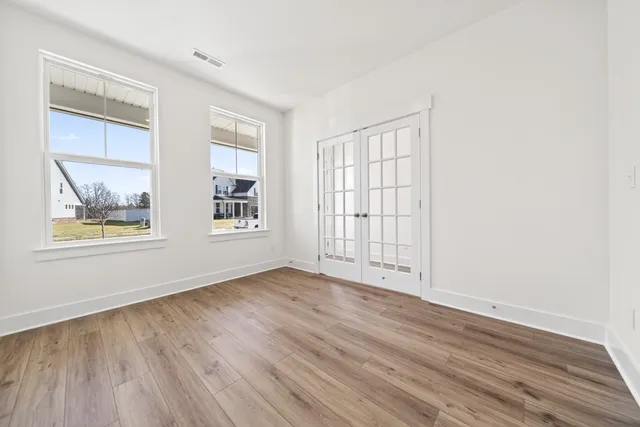 an empty room with wooden floor and windows