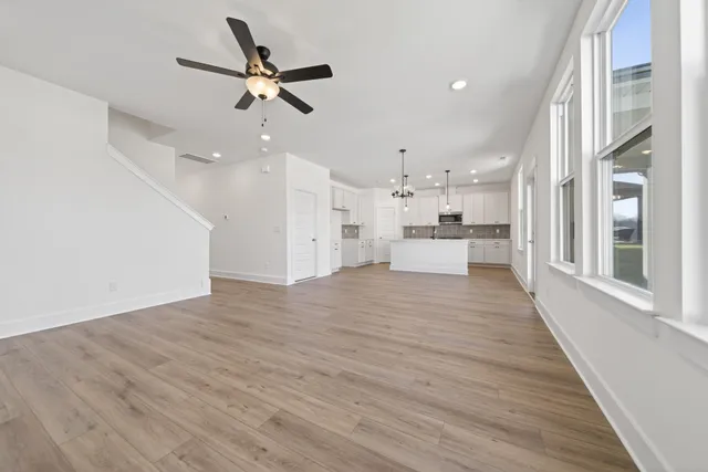 a view of empty room with wooden floor and ceiling fan