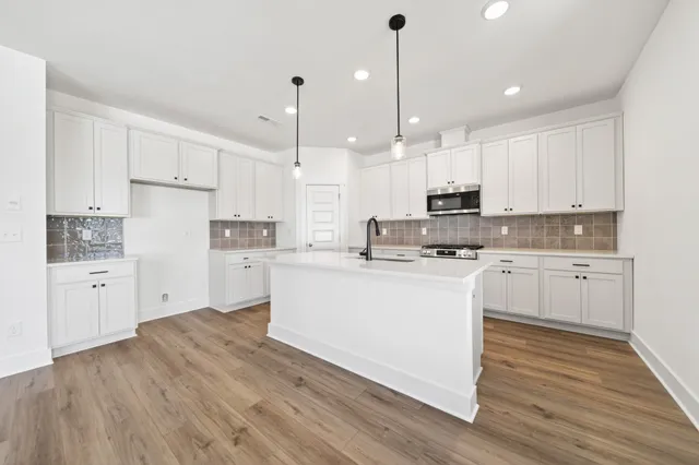 a kitchen with stainless steel appliances white cabinets granite counter tops and a hard wood floors