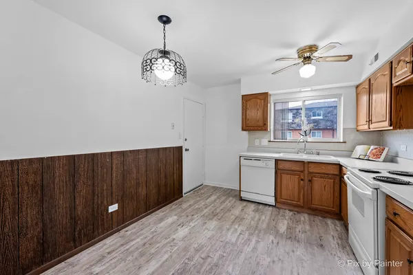 a kitchen with a chandelier fan and wooden floor