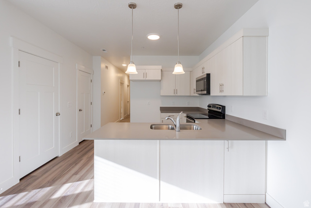 4662 Poplar Way, Unit Q301 Mapleton, UT 84664 - Photo 9 of 18 Kitchen featuring a peninsula, decorative light fixtures, stainless steel appliances, light wood-style floors, and light countertops