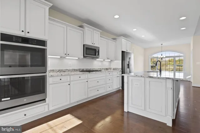 a kitchen with stainless steel appliances white cabinets and a stove top oven