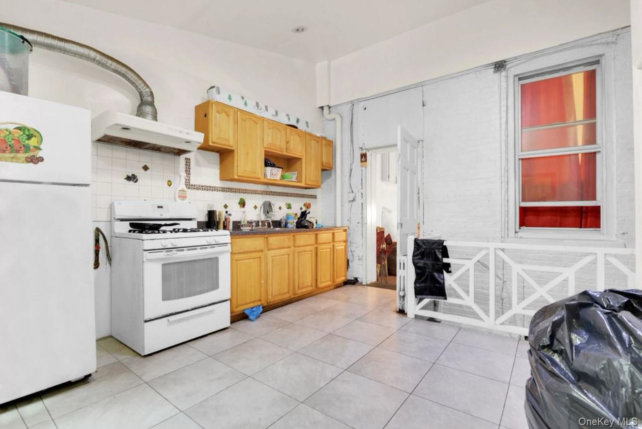 88-22 85th Street Queens, NY 11421 - Photo 11 of 33 Kitchen featuring white appliances, ventilation hood, backsplash, and light tile patterned floors