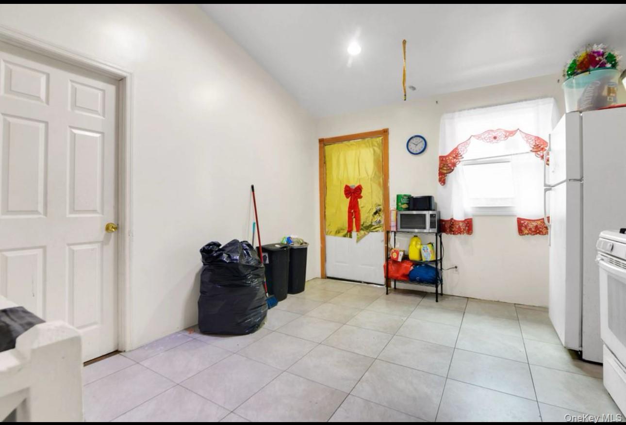 88-22 85th Street Queens, NY 11421 - Photo 12 of 33 Kitchen with light tile patterned floors, white appliances, and vaulted ceiling
