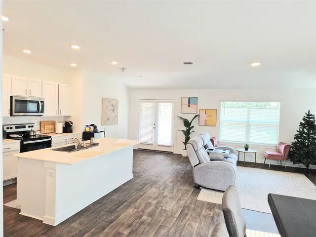 a living room with stainless steel appliances furniture a dining table and kitchen view