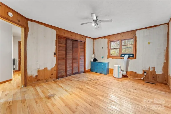 a view of empty room with wooden floor and fan