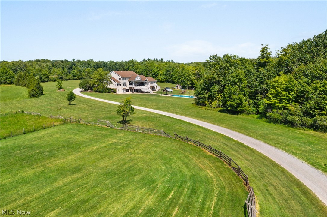 9419 Robinson Road Chardon, OH 44024 - Photo 39 of 49 Expansive green landscape featuring a gravel driveway, a large residence with multiple levels and outdoor decks, a swimming pool, and a surrounding wooded area