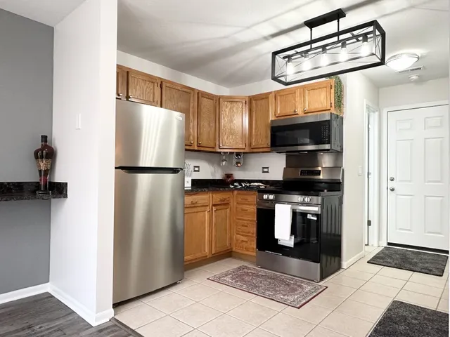 a kitchen with stainless steel appliances granite countertop a refrigerator a stove top oven a sink and dishwasher