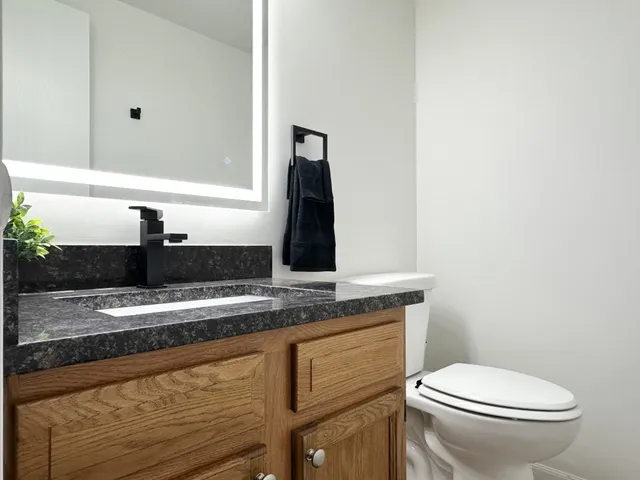 a bathroom with a granite countertop sink a toilet and mirror