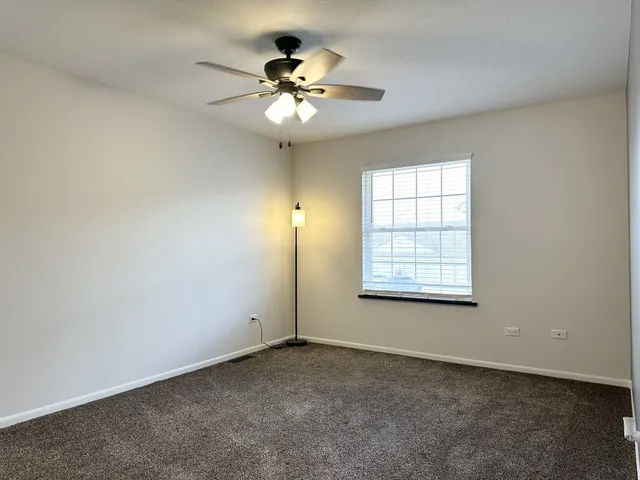 an empty room with a chandelier fan and windows