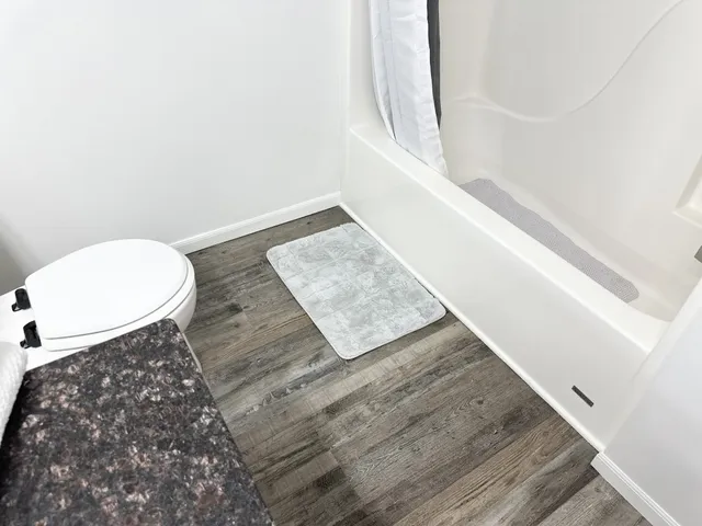 a view of a bedroom with wooden floor and bathroom