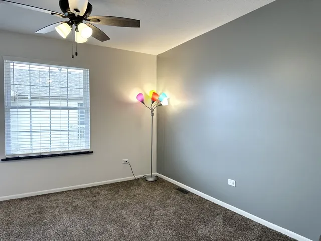 an empty room with a window and a fan