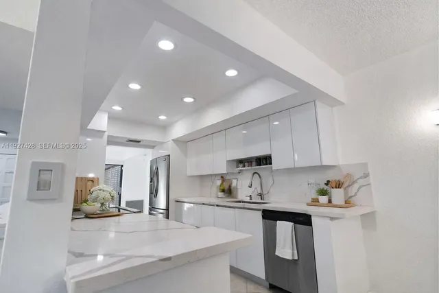 a kitchen with stainless steel appliances granite countertop a sink refrigerator and cabinets