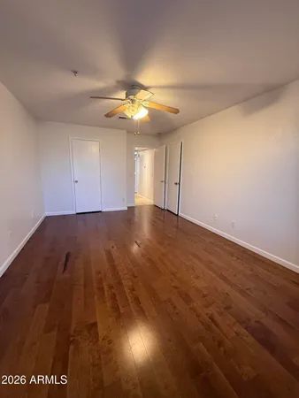 an empty room with wooden floor and fan