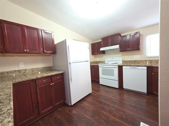 a kitchen with a refrigerator a stove a sink and wooden floor
