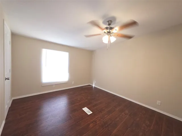 an empty room with a window and a fan