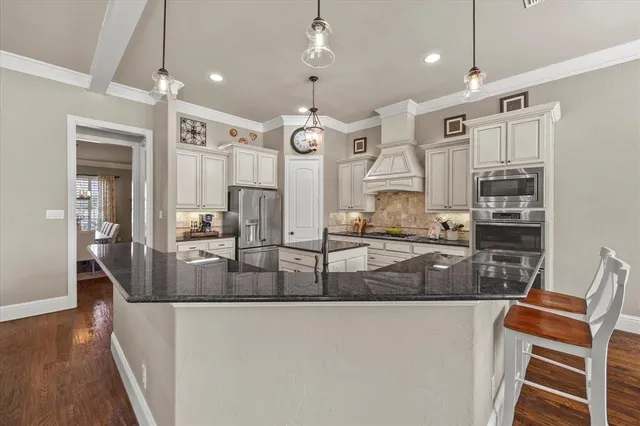 a large kitchen with granite countertop a stove a sink a refrigerator and a dining table with wooden floor