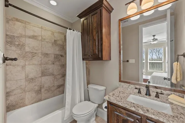 a bathroom with a granite countertop sink a toilet a mirror and shower