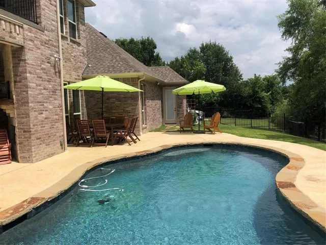 a view of swimming pool with a lounge chair and dinning table under an umbrella