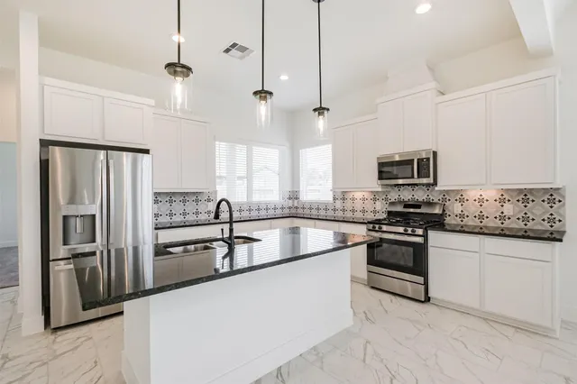 a kitchen with stainless steel appliances granite countertop a refrigerator a stove a sink and a microwave