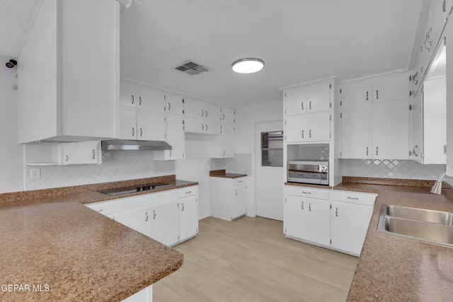 a kitchen with granite countertop white cabinets and stainless steel appliances