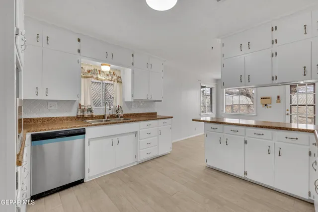 a kitchen with white cabinets and window