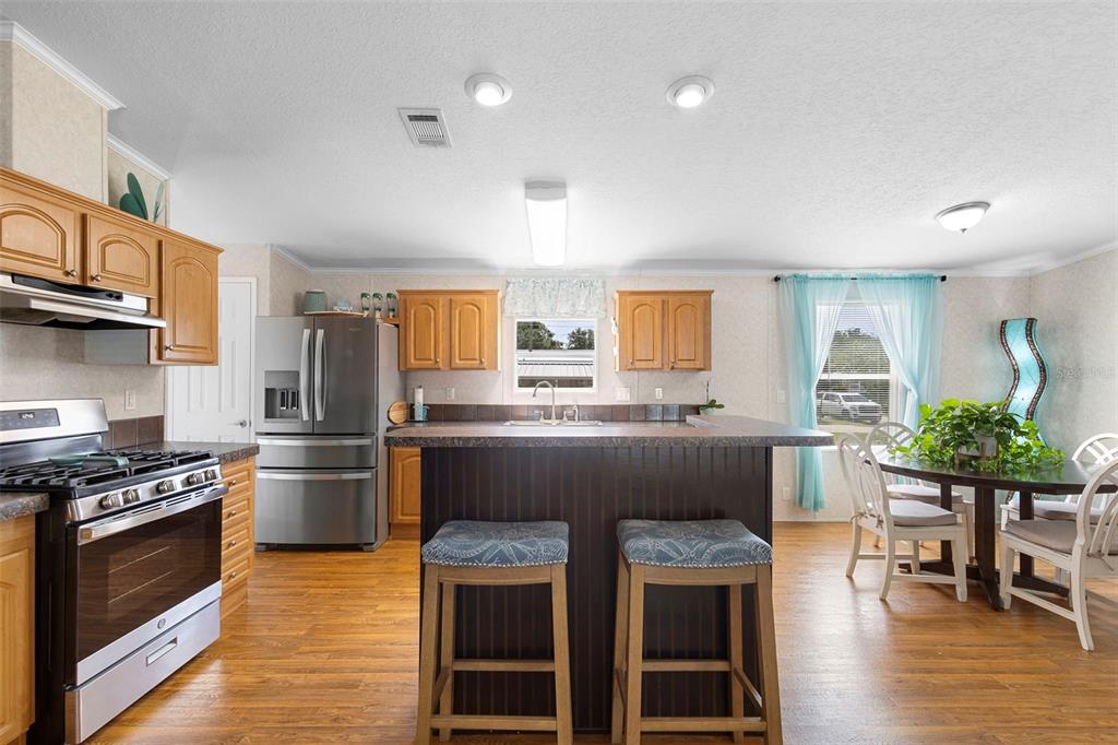 4393 Maple Avenue Edgewater, FL 32141 - Photo 6 of 41 a kitchen with stainless steel appliances a stove a sink dishwasher a refrigerator white cabinets and wooden floor