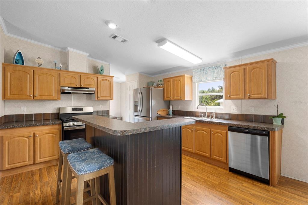 4393 Maple Avenue Edgewater, FL 32141 - Photo 8 of 41 a kitchen with stainless steel appliances granite countertop wooden cabinets a sink dishwasher a stove and a refrigerator with wooden floor