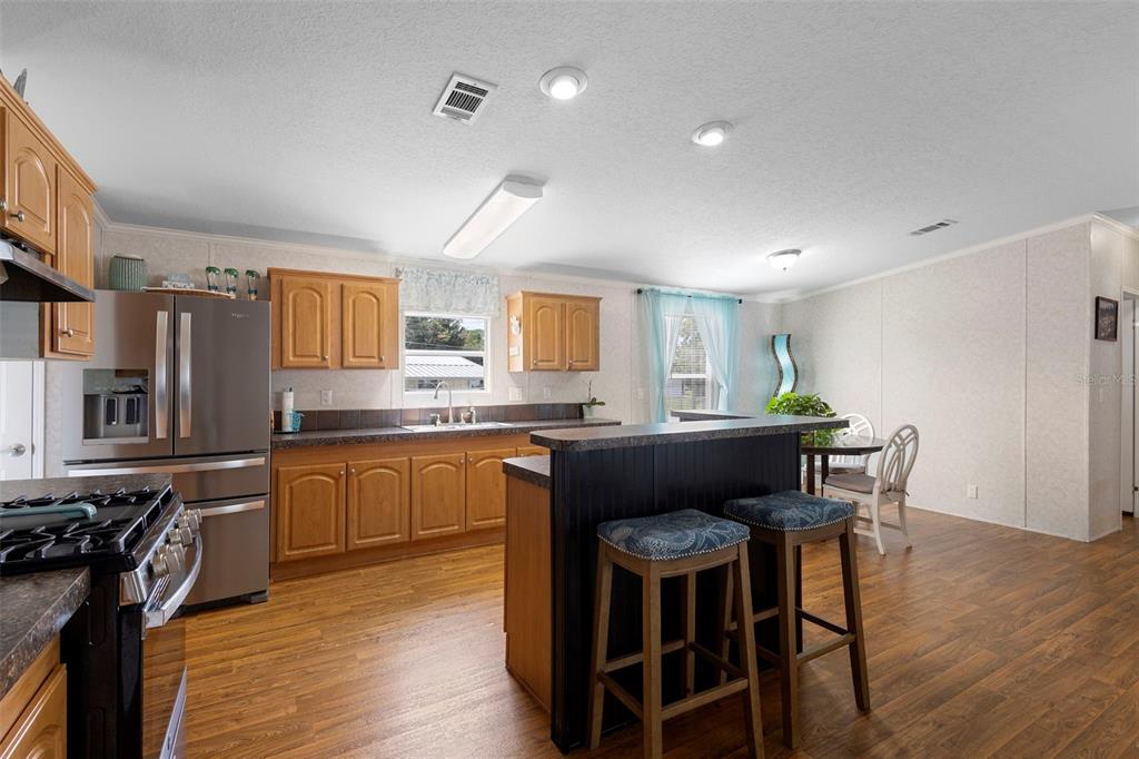 4393 Maple Avenue Edgewater, FL 32141 - Photo 9 of 41 a kitchen with granite countertop a table chairs stove a sink dishwasher and cabinets
