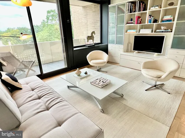 a living room with furniture a flat screen tv and a floor to ceiling window