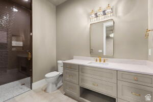 1141 East Lost Ridge Drive Washington, UT 84780 - Photo 83 of 108 Spacious bathroom featuring a glass-enclosed shower with dark tile, a light-colored vanity with ample storage, a white countertop, and gold-finish fixtures
