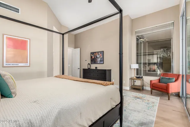 a bedroom with a bed and large windows with chair