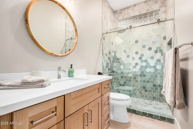 a bathroom with a granite countertop sink toilet a mirror and shower