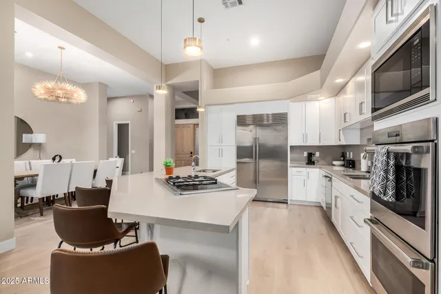 a large kitchen with stainless steel appliances kitchen island granite countertop a lot of cabinets a refrigerator and a stove