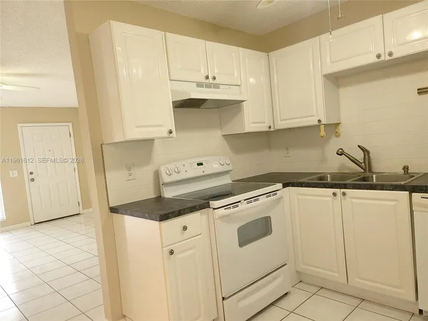 a kitchen with granite countertop white cabinets and white appliances