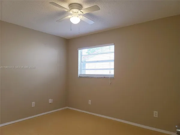 an empty room with a window and a fan