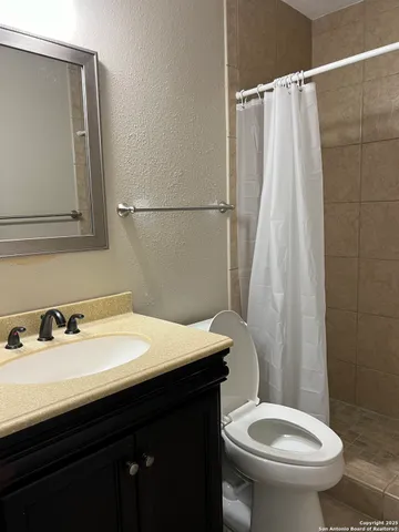 a bathroom with a sink a toilet and shower curtain