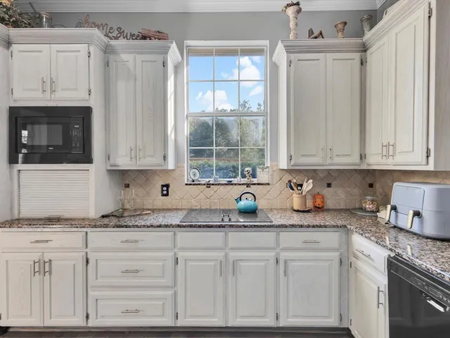 a kitchen with stainless steel appliances granite countertop white cabinets sink and granite counter tops