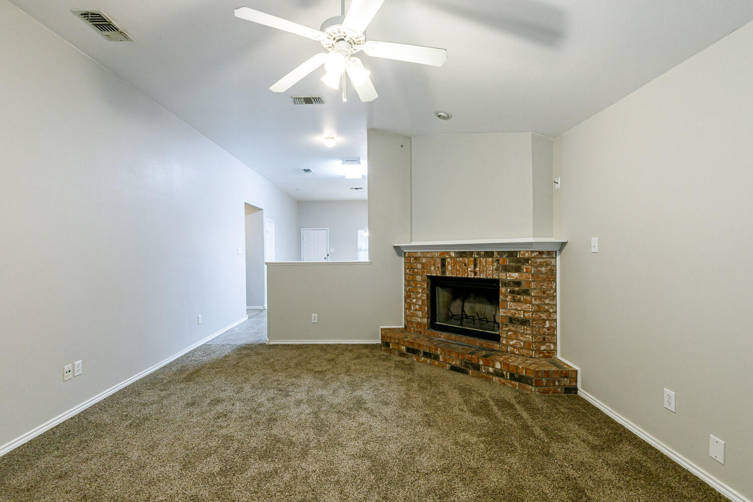6520 92nd Street Lubbock, TX 79424 - Photo 7 of 30 an empty room with a fireplace and a ceiling fan