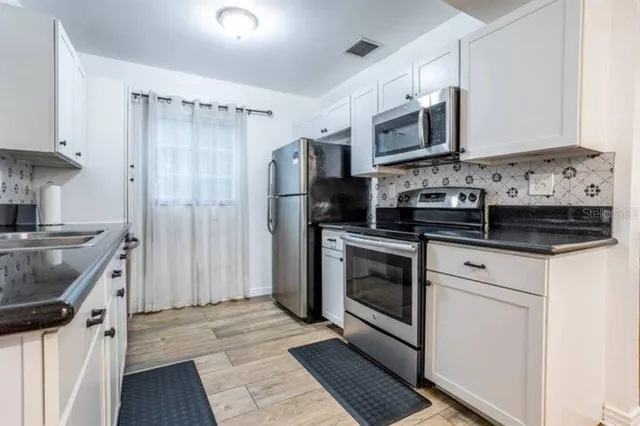 a kitchen with stainless steel appliances granite countertop a stove a microwave and a refrigerator